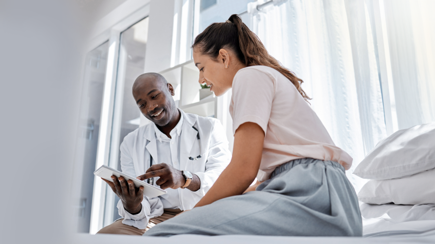 A healthcare professional reviewing patient data with a patient alongside an AI interface, symbolizing the shift from AI as tool to AI as teammate.